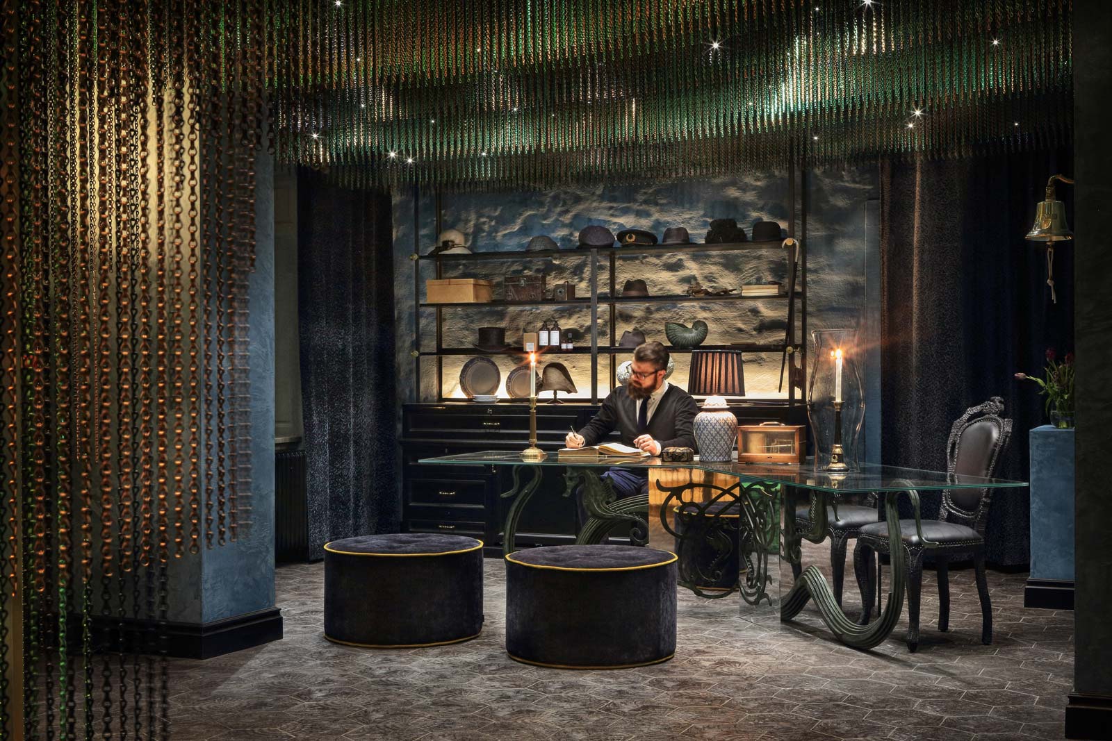 Modern hotellbar med unik belysning och avslappnad atmosfär, där en man arbetar vid ett bord.