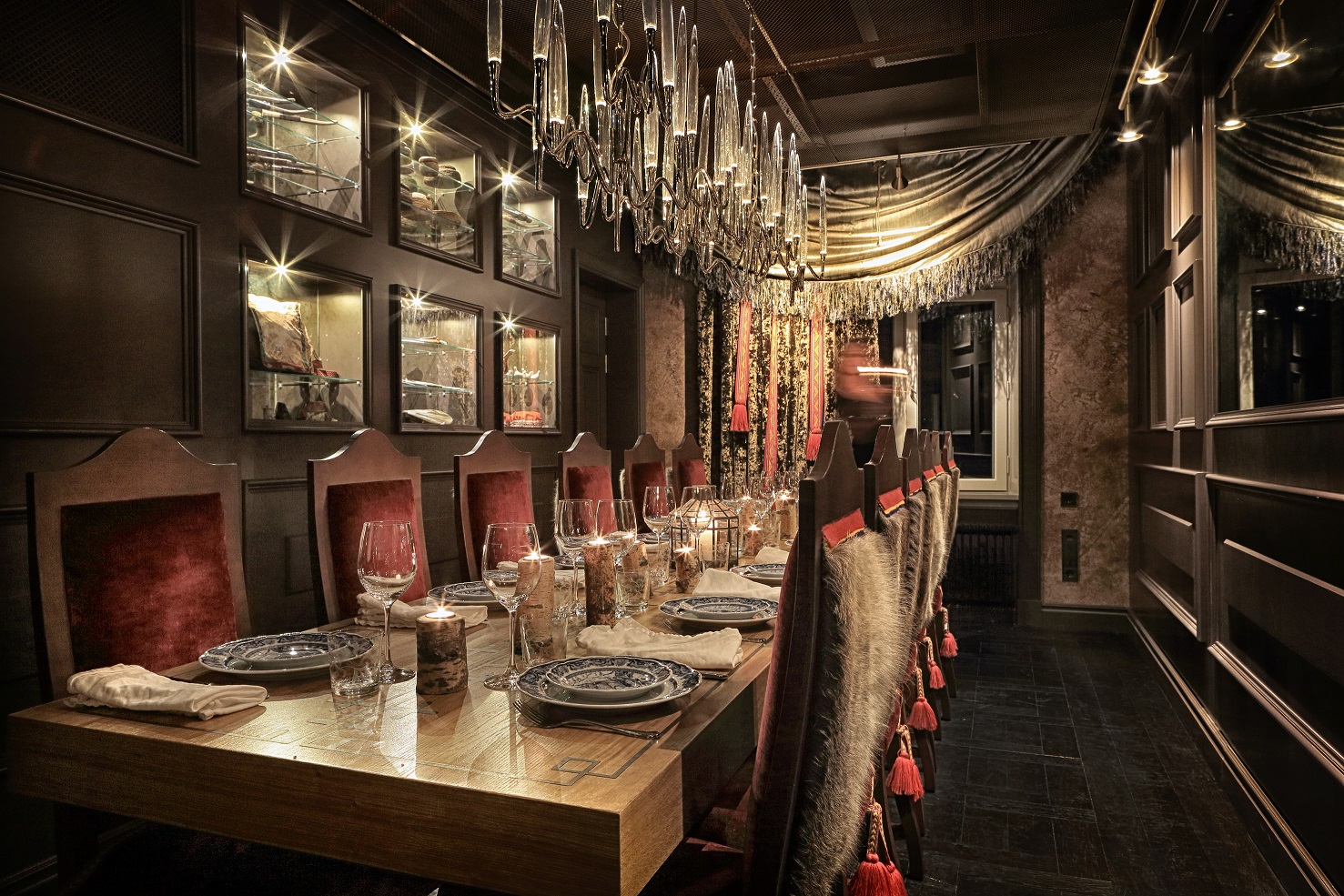 Raffinerad matsal inredd för middagsfest med röda stolar, kristallkronor och elegant dukade bord.